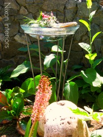 Glass bowl water fountain in garden filled with beach rocks, beach glass and abalone shell